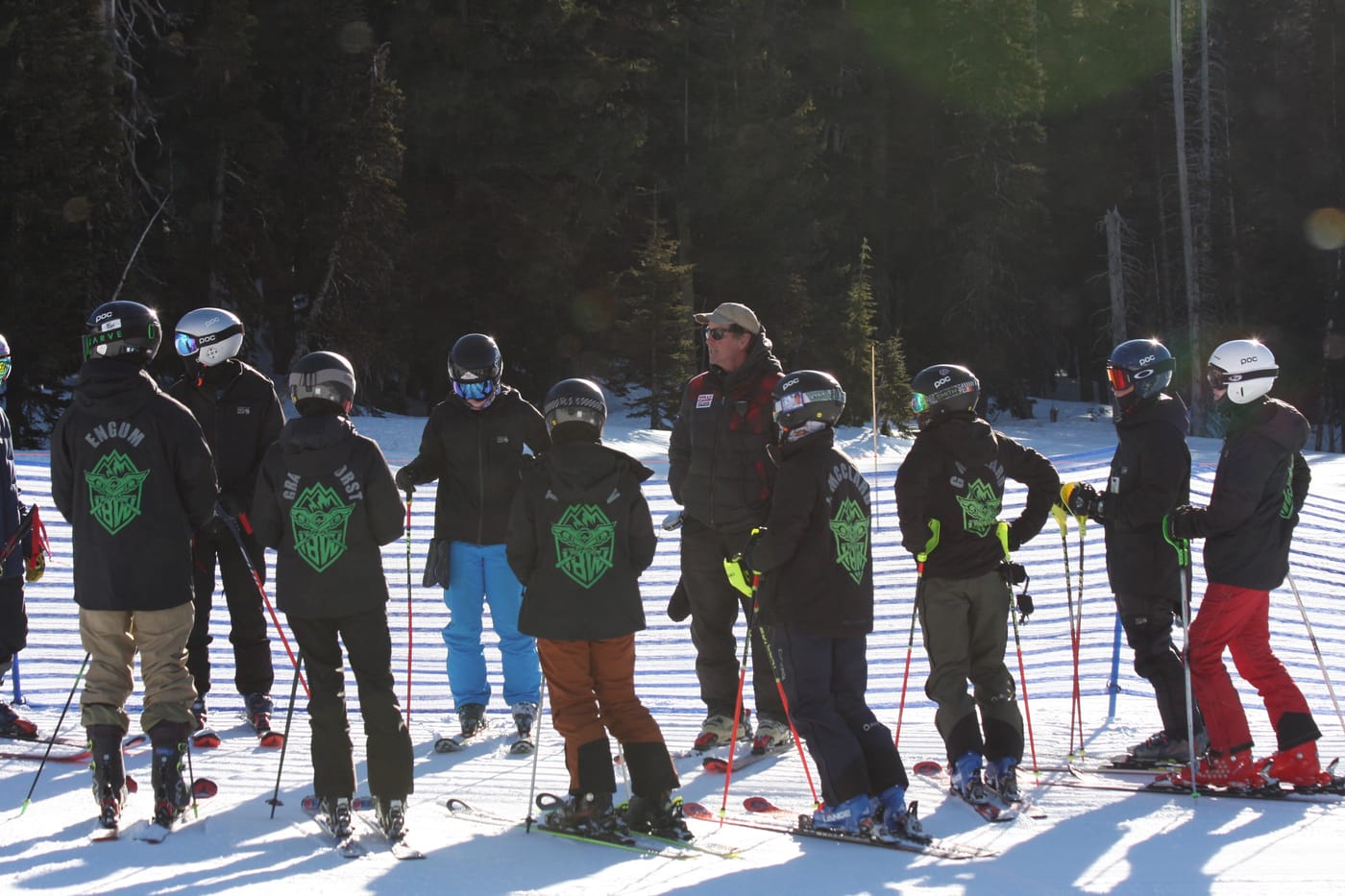 The team lined up along the course fence in low winter sun, Guardians crests across the backs of their jackets, a coach talking them through the line